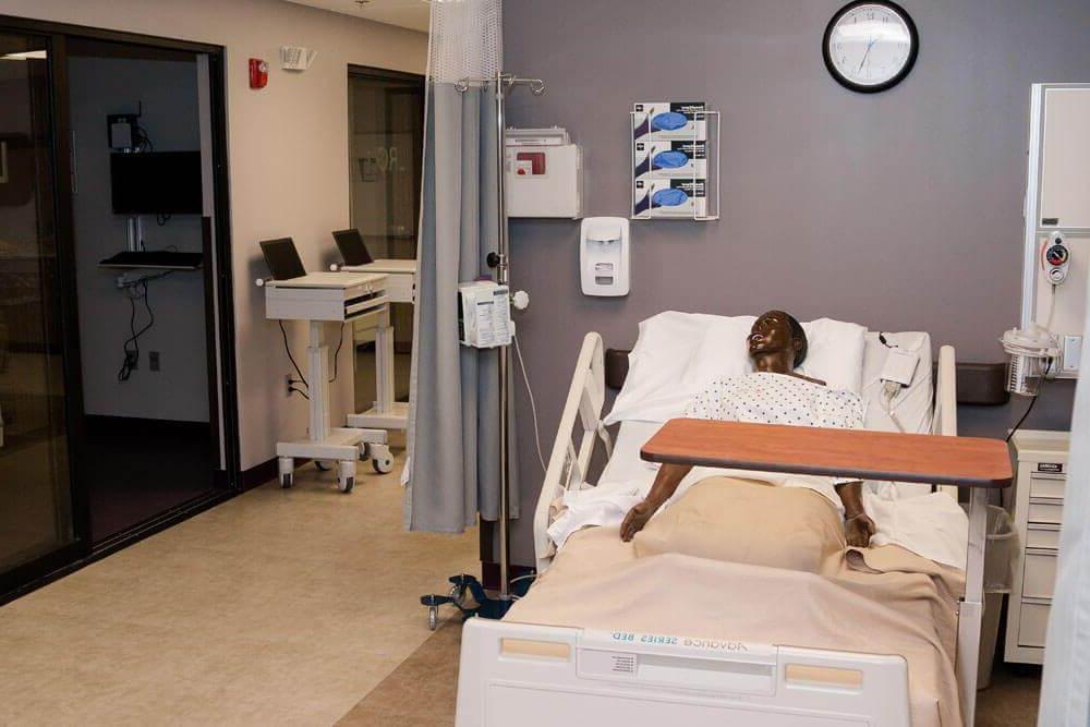 Mannequin lays in hospital bed in simulation hospital room