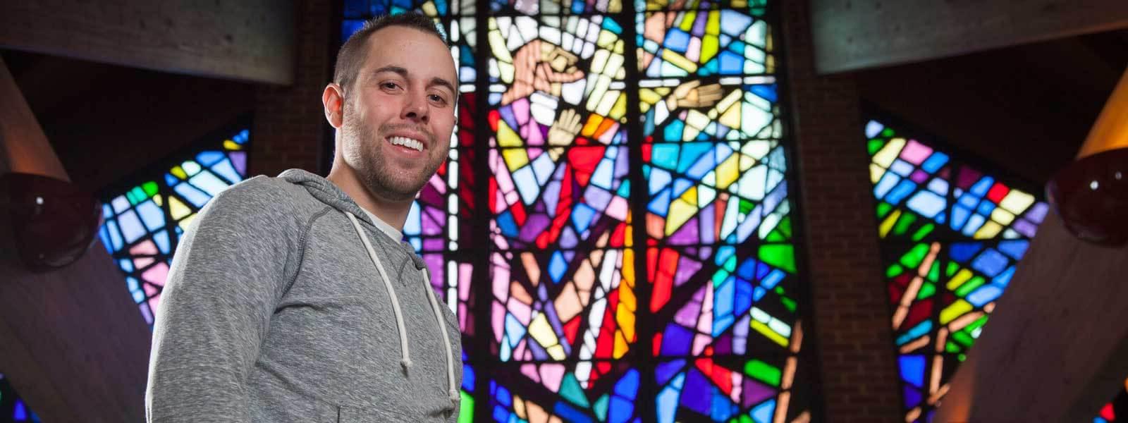 student standing in front of stained glass window in Randolph Chapel
