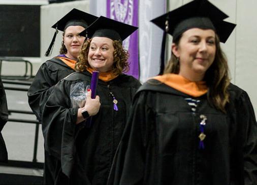 MSN grads smile while walking in commencement ceremony
