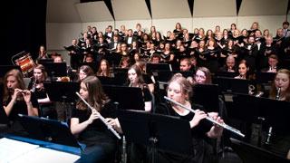 Instrumental and choral ensembles perform on stage together