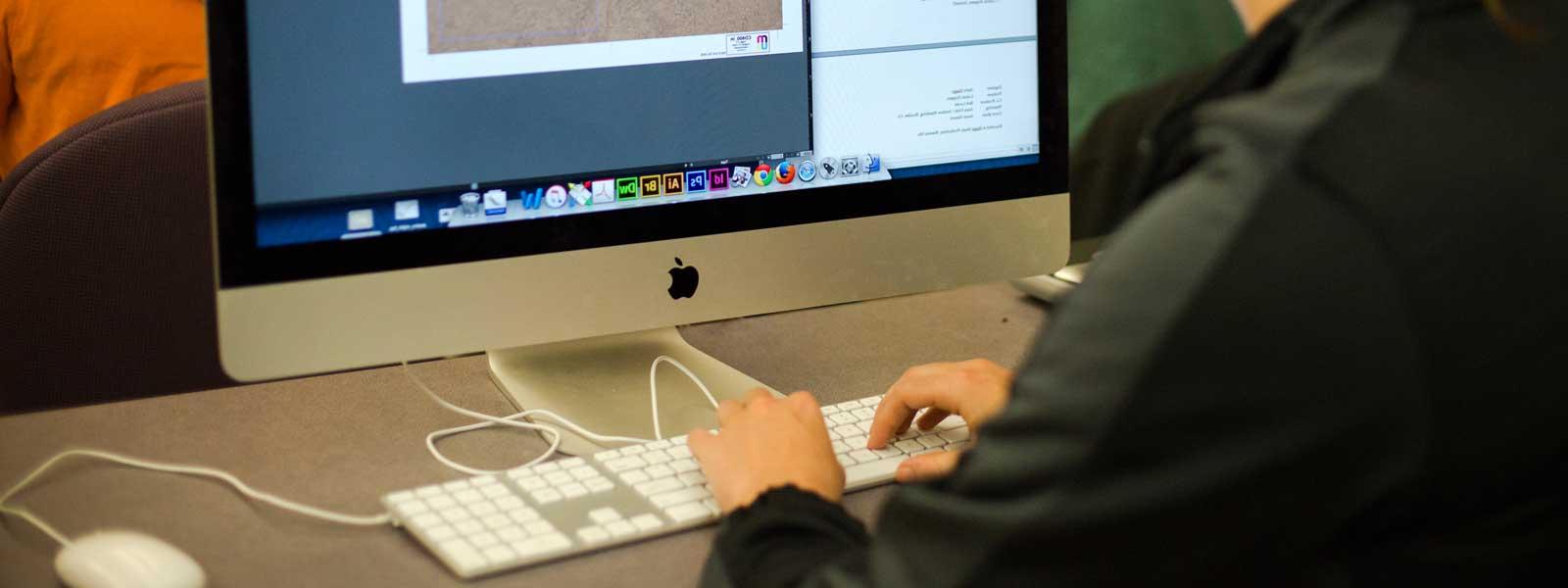 在大型Mac电脑上从事平面设计项目的学生