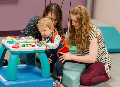 physical therapy student and professor work with toddler learning to walk