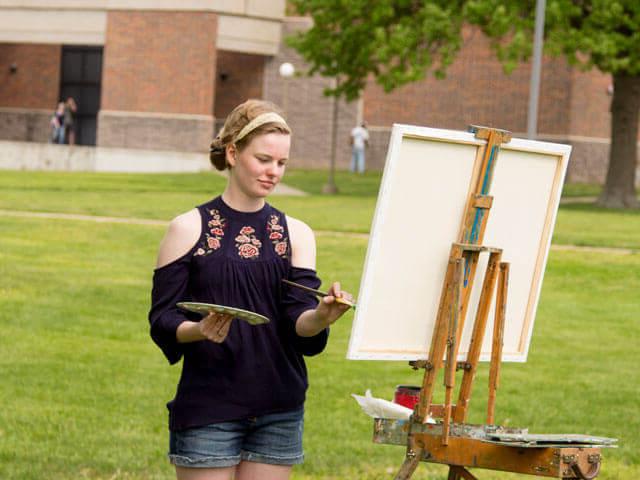 Female art student working on painting outside