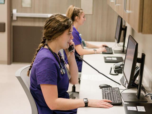 students wearing purple scrubs work at computers