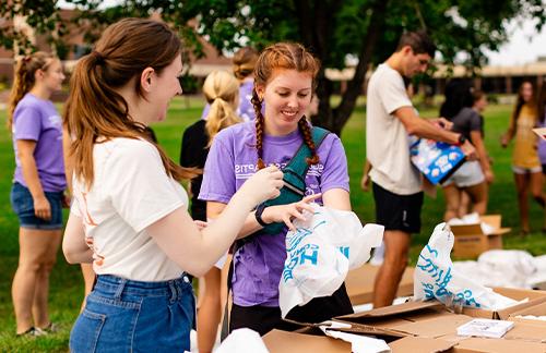 female students pack grocery bags during community outreach event