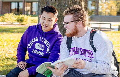 two male students reading a book on SBU Bolivar Campus